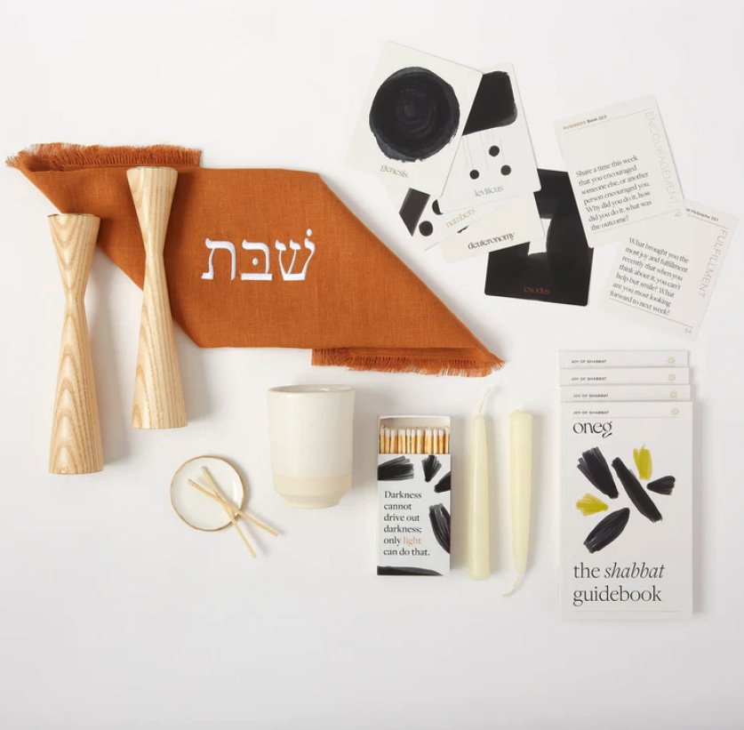 Oneg Home's Shabbat kit: candlesticks, a challah cover, candles, and a guidebook.