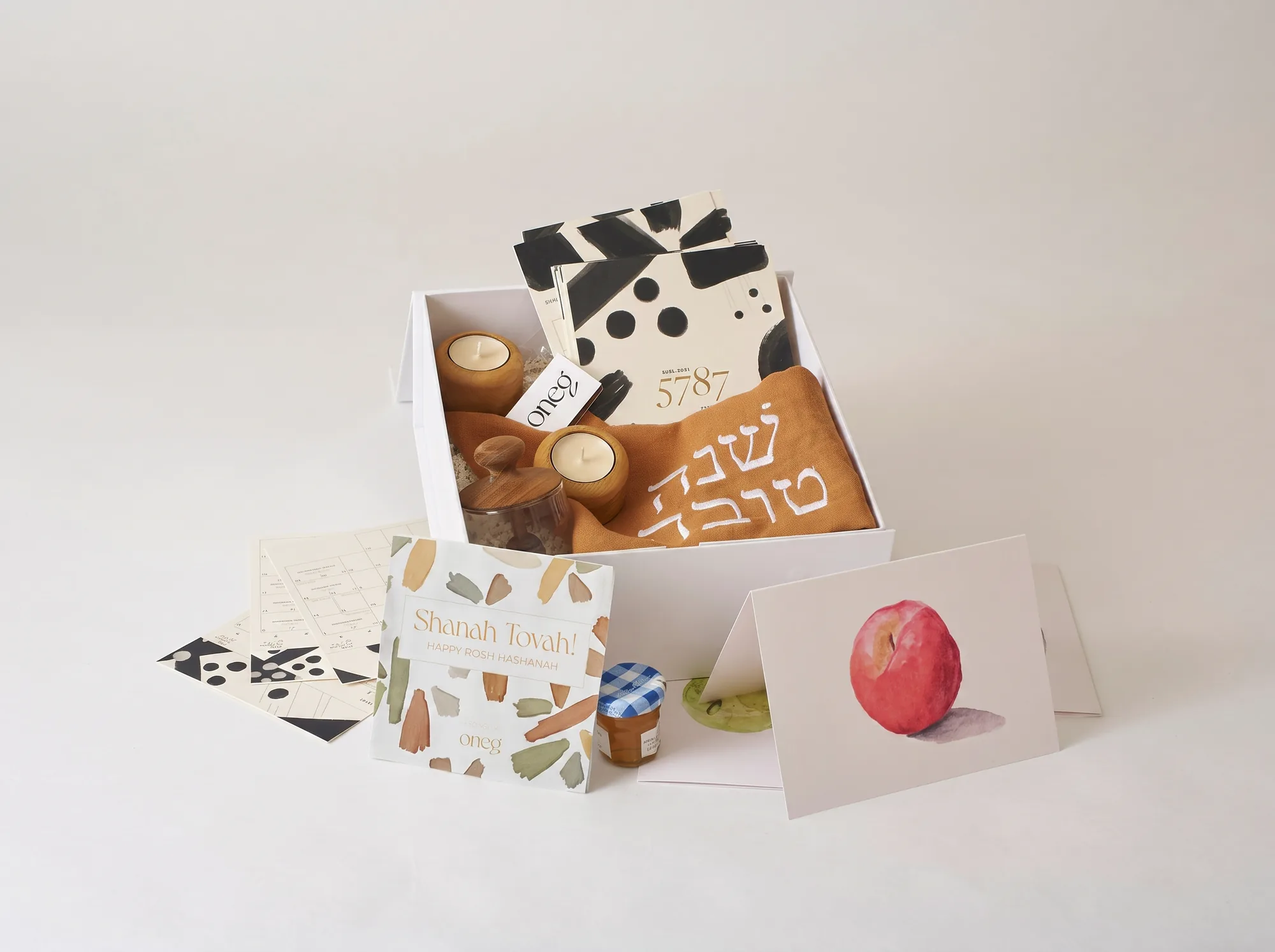 The Rosh Hashanah Celebrate Box with the cinnamon round challah cover, honey jar, calendar, and greeting cards, photographed in studio.