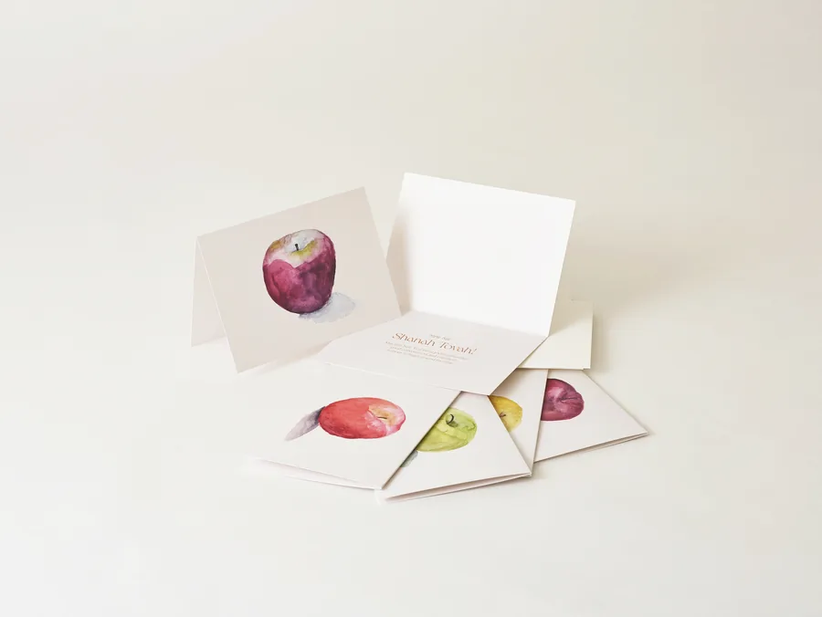 The New Year's greeting cards fanned out, each with a watercolor apple.